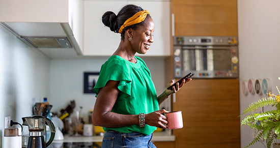 Woman in her kitchen looking at her phone