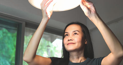 Woman Installing Energy Efficient Bulb